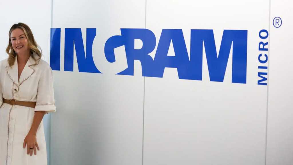 A photograph of Ingram Micro's Hope McGarry standing in front of the Ingram Micro logo.